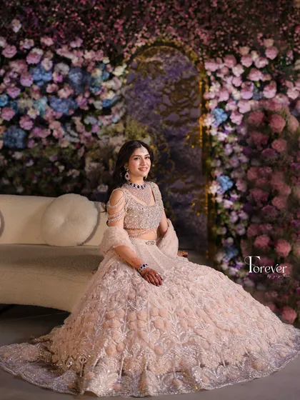 The bride seated gracefully on a sofa against a wall of flowers. This setup provides a perfect, picturesque moment, combining comfort with high-end floral design.