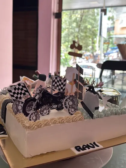 A close-up of the motorcycle section of the multi-themed cake. The checkered flags and detailed bike topper are perfect for a racing enthusiast.