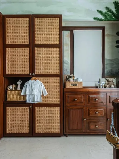 Storage is key in any nursery. I designed this custom floor-to-ceiling wardrobe with natural cane paneling to complement the wooden crib and changing table. It provides ample space while adding to the room's warm, natural aesthetic.