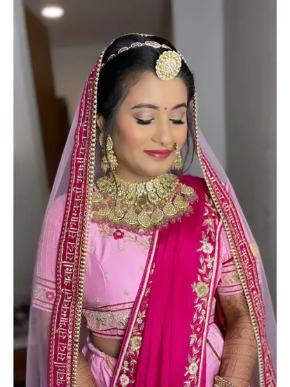 The complete bridal look with her dupatta set. The soft pink makeup with a hint of shimmer on the eyes perfectly complements her traditional jewelry and radiant smile.