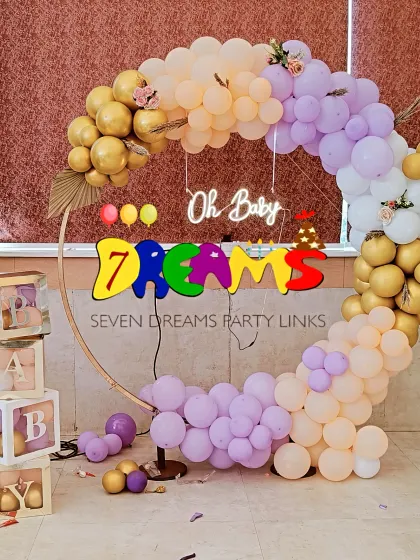 This is a popular modern baby shower design. I use a circular gold-tone ring, an organic arch of pastel and metallic balloons, and a custom "Oh Baby" neon sign. The transparent "BABY" blocks can be filled with balloons matching your color scheme.