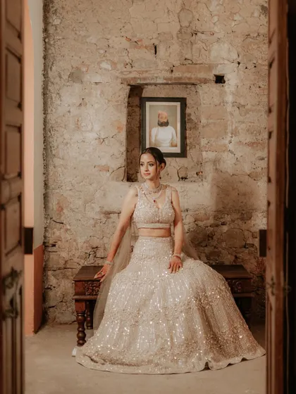 A full-length portrait of Leesha in her sparkling engagement lehenga, framed by a doorway in a stone-walled, heritage-style venue.