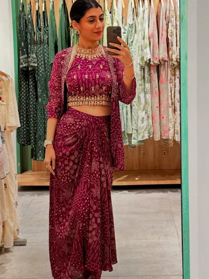A mirror selfie from a retail styling event, showcasing a beautiful magenta bandhani-print indo-western outfit, perfect for a modern festive look.