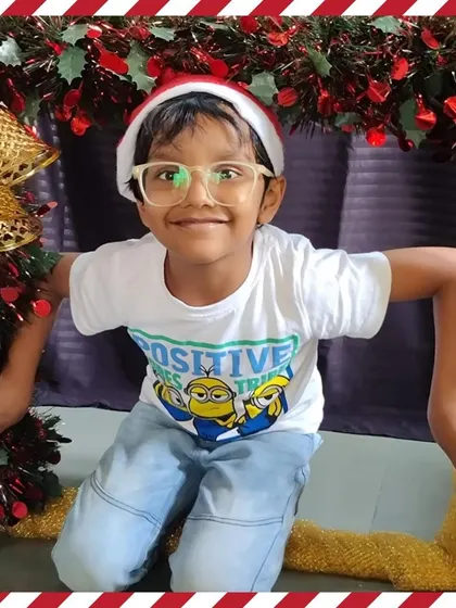 A happy boy with a big smile poses for his Christmas photo.