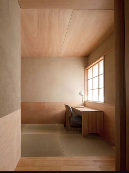 This minimalist study nook within a bedroom uses a consistent palette of light wood and textured plaster. The design creates a tranquil and focused workspace that feels integrated with the rest of the room.