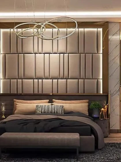 This bedroom design features a striking padded headboard with vertical grooves and a gold metal frame. The combination of marble walls, warm lighting, and plush textiles creates an atmosphere of sophisticated comfort.