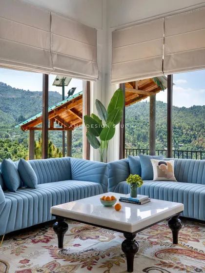 A closer look at the plush, channel-tufted blue sofas set against floor-to-ceiling windows. This design choice maximizes both comfort and the breathtaking mountain scenery.