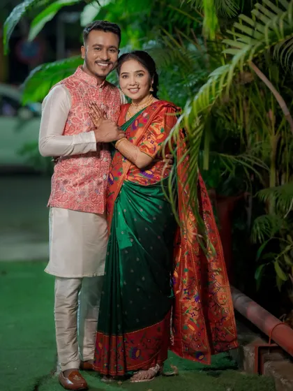A full-length portrait of the couple, showcasing their traditional Maharashtrian attire. The groom's printed jacket and the bride's Paithani saree are beautifully captured.