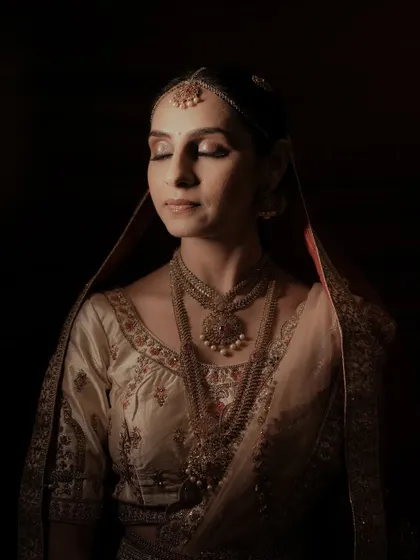 A stunning close-up of the bride, with dramatic lighting highlighting her intricate jewelry and serene expression.