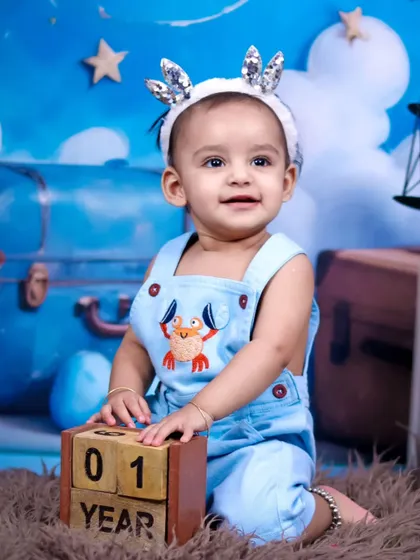 A happy one-year-old boy celebrating his birthday with our sky and teddy bear theme.