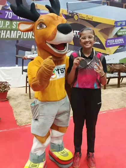 Samriddhi Sharma celebrating her bronze medal win at the UP State Championship. Posing with the event mascot, this picture captures the joy and pride of her significant achievement.