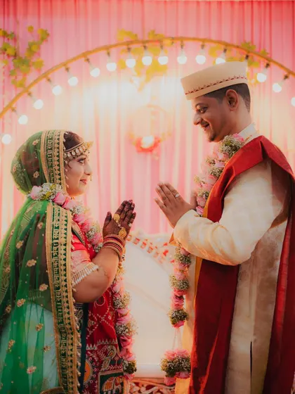 The bride and groom greet each other with a respectful 'namaste' during their wedding ceremony.