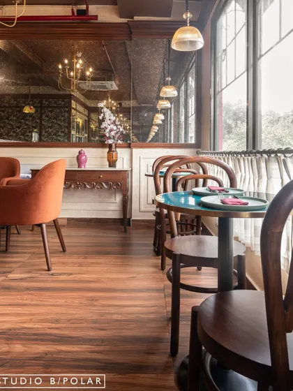 The interior of Melthouse evokes the warmth of a classic European cafe with its rich wood flooring, vintage-style furniture, and large windows. The antique mirror reflects the space, adding depth and a sense of history.