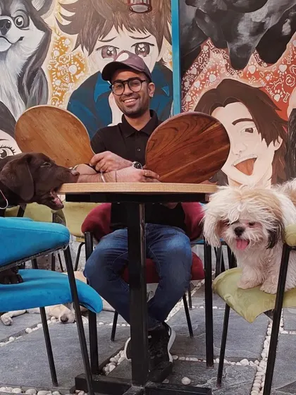 Our co-founder Nikhil enjoying a playful moment with two of our resident dogs at the table.