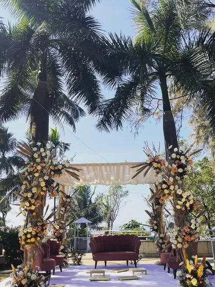 A beautiful mandap setup for a daytime ceremony with a view of the sea. The design uses pampas grass and dried florals for a bohemian-chic vibe, perfectly complementing the natural surroundings.
