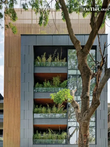 A modern apartment building where the balconies are designed as deep planters, allowing residents to have their own gardens. The integration of wood and slate-colored panels complements the natural greenery.