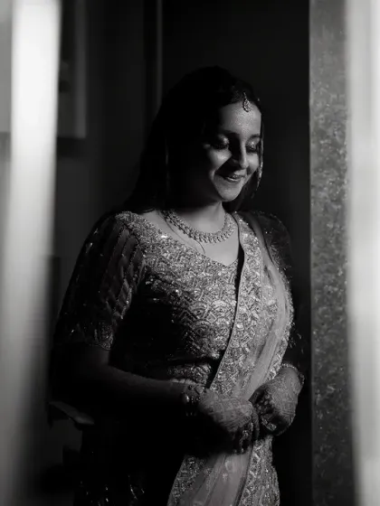 A soft and intimate black and white portrait, shot through a doorway. This framing creates a sense of looking in on a private, happy moment.