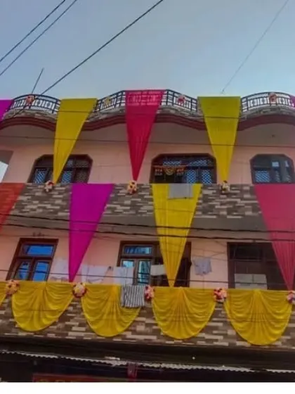 A house facade decorated with drapes in multiple colors, including pink, yellow, and orange.