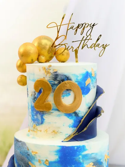 A close-up of the bold blue and gold 20th birthday cake, highlighting the hand-detailed textures and golden number topper.