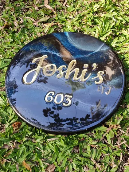 A close-up shot of the glossy finish on a galaxy-themed nameplate. The high-shine resin reflects the surroundings, adding another layer of depth and making the golden acrylic lettering pop.