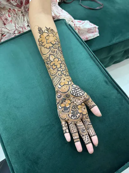 A full view of the intricate floral henna design, showcasing the flow from the arm to the hand.