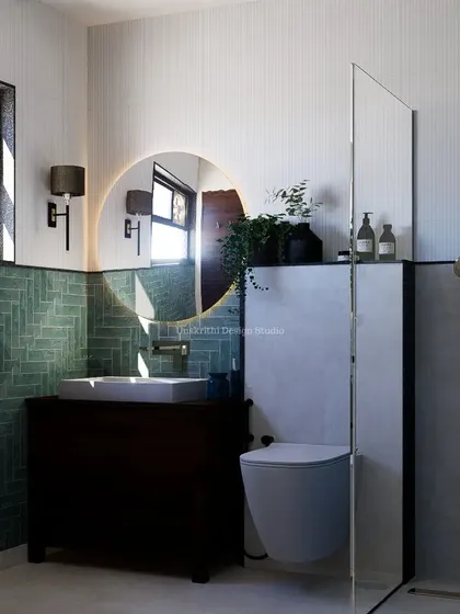 This bathroom design features aqua subway tiles laid in a herringbone pattern, creating a beautiful feature wall. Paired with a backlit mirror and simple, textured white tiles, it creates a standard of elegance that is both modern and timeless.