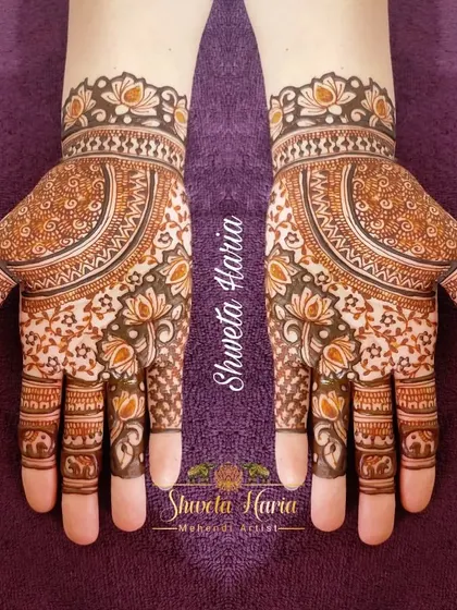 This traditional design is filled with delicate details. It features a large central mandala with lotus and elephant motifs woven into the pattern on the fingers and wrist.