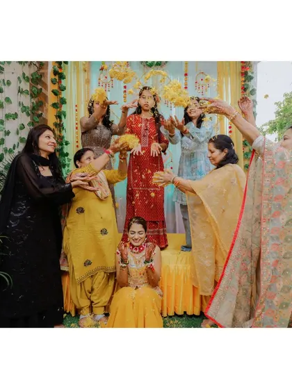 A fun moment of the bride being showered with flower petals by her family during the Haldi ceremony.