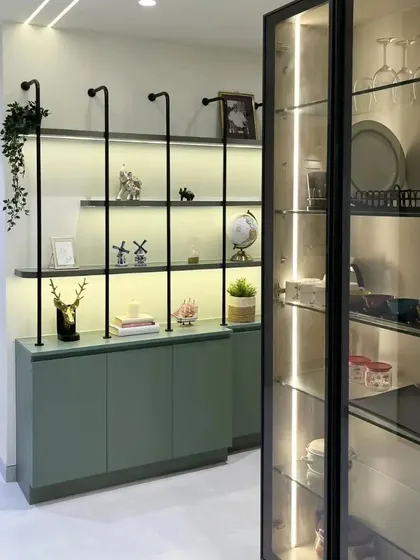 A minimal foyer leads into a colorful living space, with a green crockery unit featuring metal accents providing a beautiful transition.