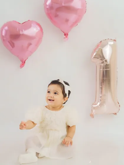 Looking up with wonder. This candid shot from a first birthday session shows the baby's curiosity and joy amidst the celebration.