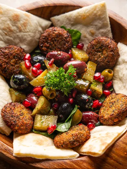 A rustic falafel platter with pita bread and pickled vegetables. We use natural textures and overhead lighting to create an authentic, wholesome feel.
