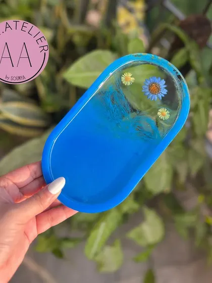 A striking blue oval trinket tray. The deep color contrasts beautifully with the delicate flowers, creating a captivating piece.
