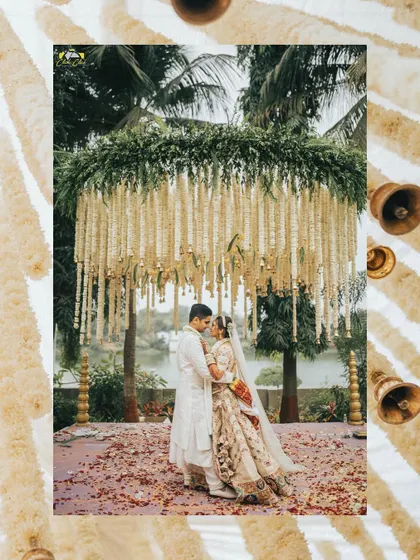 A stunning couple portrait under a magnificent mandap of hanging floral strings. This wide shot captures the grandeur of the decor and the romance of the moment.