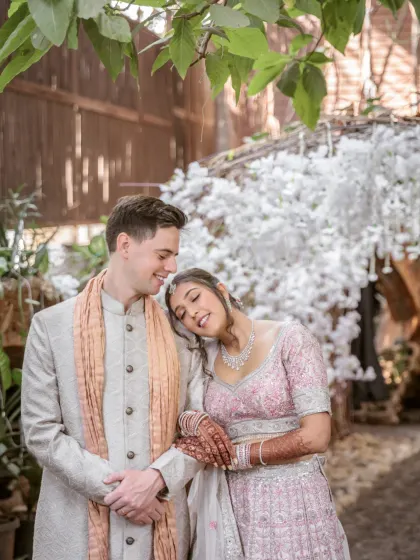 A sweet and peaceful moment, with the bride resting her head on the groom's shoulder under a canopy of white flowers.