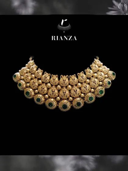 A grand gold necklace featuring intricate nakshi work and studded with green stones. This type of design is inspired by South Indian temple jewellery and is perfect for a traditional ceremony.
