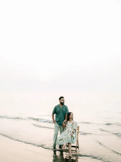A wide-angle, minimalist shot of the couple on the beach, emphasizing the vastness of the ocean and their connection within it.