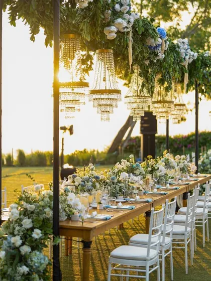 Another view of the stunning outdoor dining setup at sunset. The combination of the warm light, chandeliers, and florals creates an incredibly romantic atmosphere.