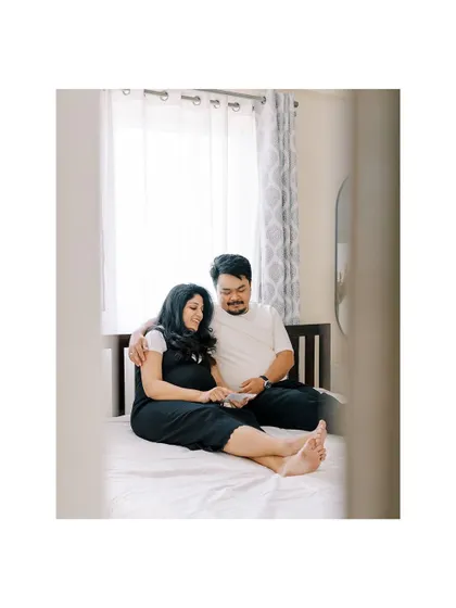 A wider shot of a couple on their bed, looking at the ultrasound scan. This image captures not just the moment, but also the comfortable, personal setting of their bedroom.