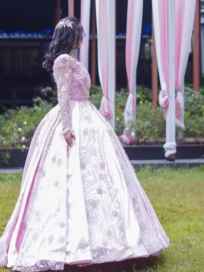 The back view of the stunning pink ball gown, showcasing its elegant silhouette against a beautiful garden backdrop. This gown is designed to make a statement from every angle.