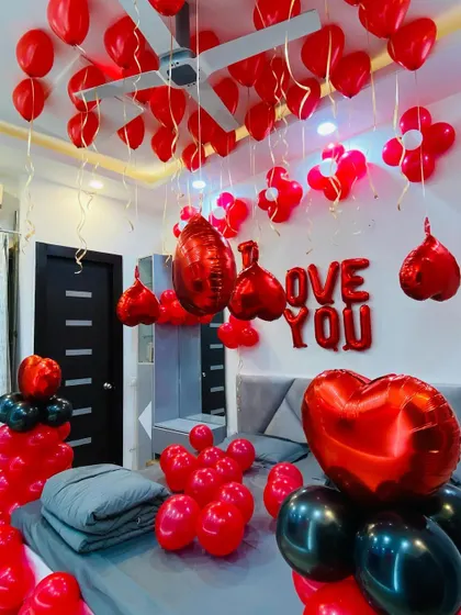 Another perspective of the red and black romantic room setup, highlighting the heart-shaped foil balloons.