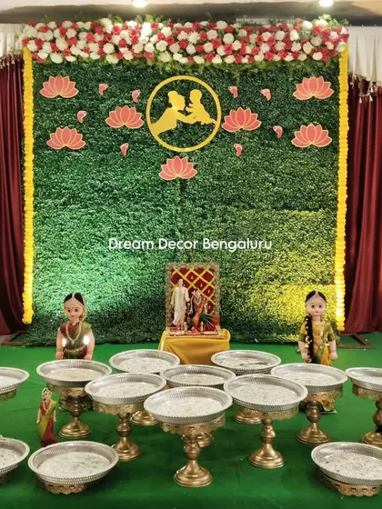 A simple yet elegant baby shower setup with an artificial green wall backdrop. The lotus cutouts and traditional dolls (Marapachi Bommai) add a touch of tradition and charm.