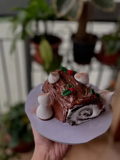 My Bûche de Noël, also known as a Yule log cake, features a chocolate sponge roll with cream filling, covered in chocolate ganache and decorated with meringue mushrooms.