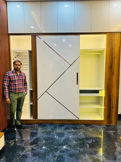 A wider view of the geometric sliding wardrobe, showing how it fits into the room. The side wall is finished with fluted wooden panels that match the wardrobe frame.
