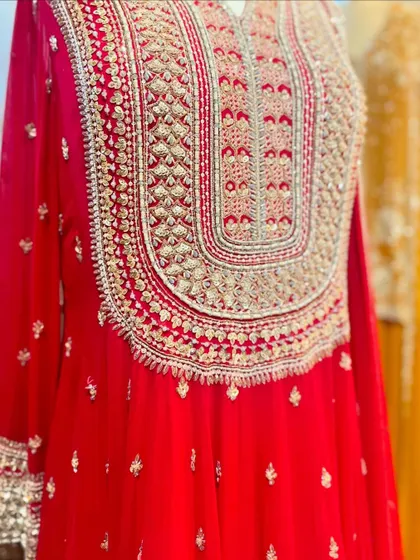 A detailed shot of the heavy embroidery on a bright red kurta, perfect for a bride or wedding guest.