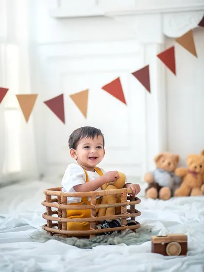 A happy little boy in a basket, surrounded by teddy bears. This is a classic and timeless setup for a sitter or first birthday session.