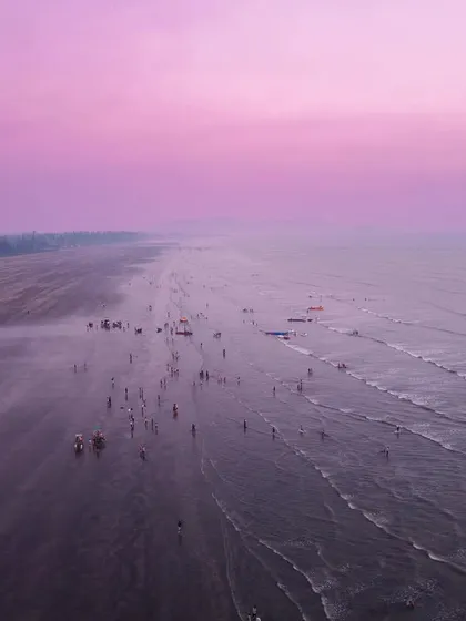 An aerial view of a beach, edited with a strong magenta tint to create a surreal, Mars-like landscape.