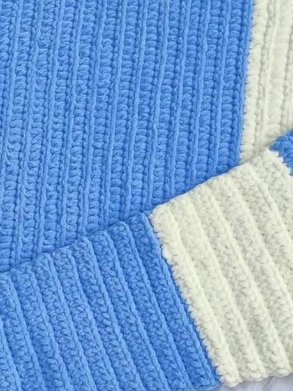 The finished blue and white baby blanket, folded and ready to keep a newborn warm.