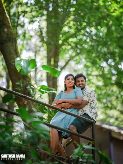 A lovely portrait of a couple embracing on a staircase, framed by natural foliage.