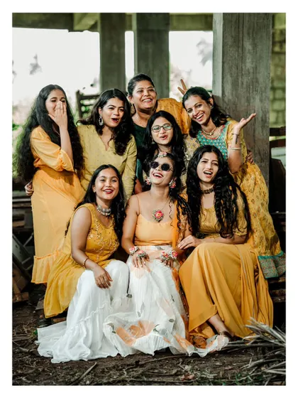 A happy group photo of the bride and her bride tribe, all dressed in yellow for the Haldi ceremony.