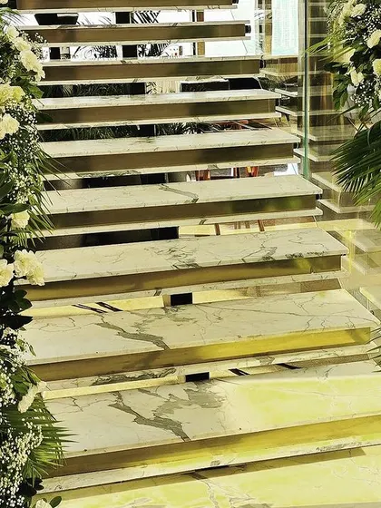 A staircase decorated with arches of white and green florals, transforming a functional space into a beautiful part of the event decor.